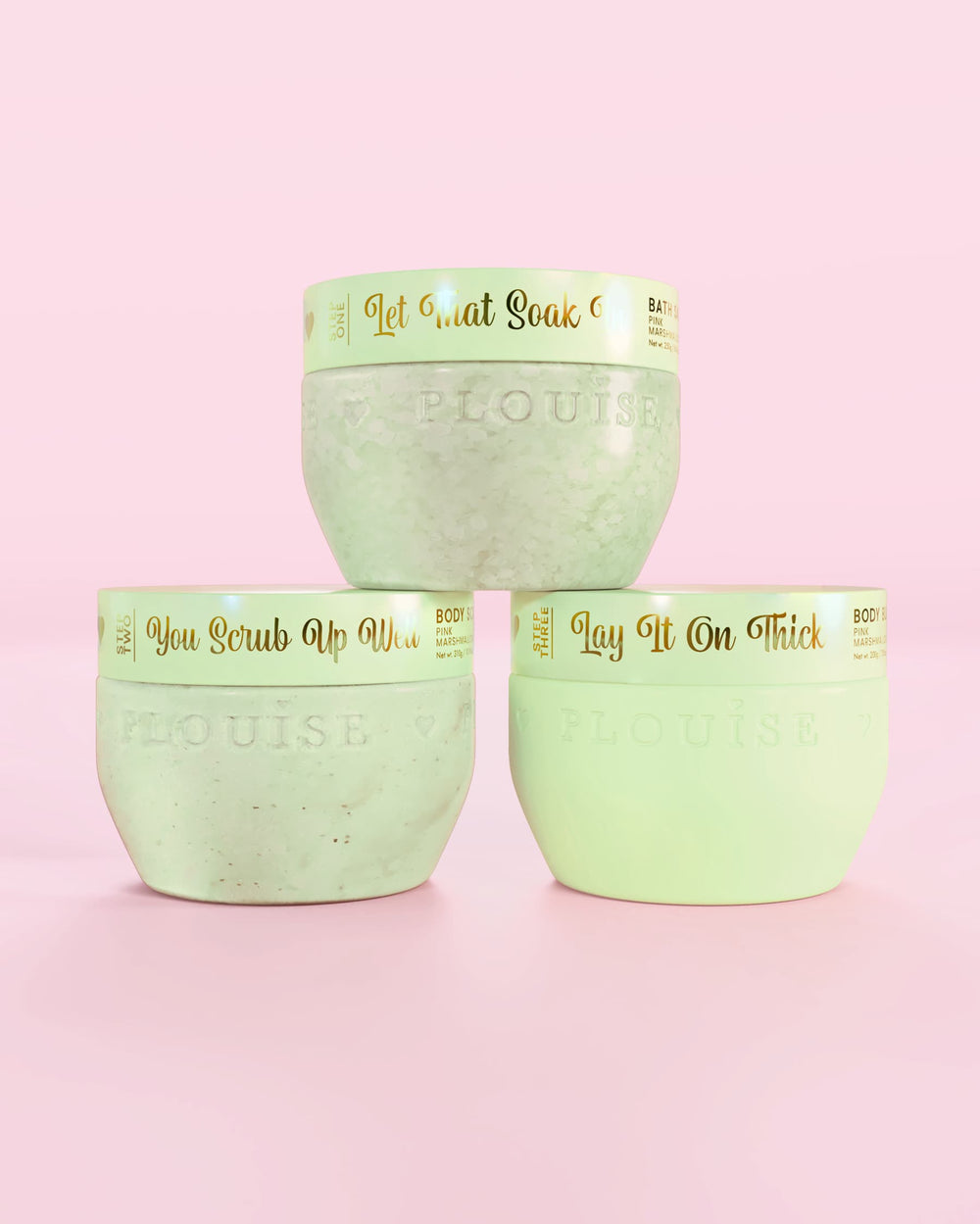 Trois contenants verts de fraises enrobées de chocolat P.Louise Hop Into Self-Care comprenant des sels de bain, un gommage corporel et du beurre corporel avec un texte doré sur fond rose
