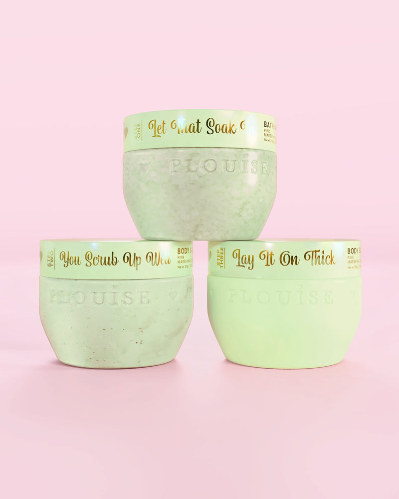 Trois contenants verts de fraises enrobées de chocolat P.Louise Hop Into Self-Care comprenant des sels de bain, un gommage corporel et du beurre corporel avec un texte doré sur fond rose