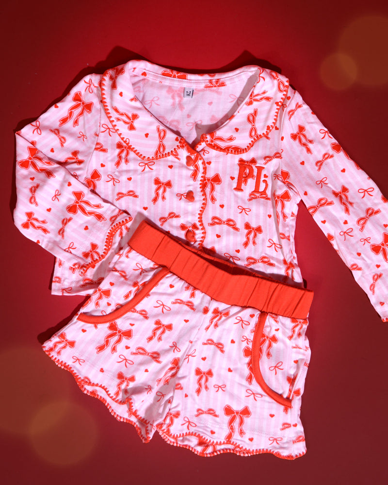 Ensemble de pyjamas de Noël pour enfants à rayures roses et blanches avec des motifs d'arcs rouges sur un fond rouge