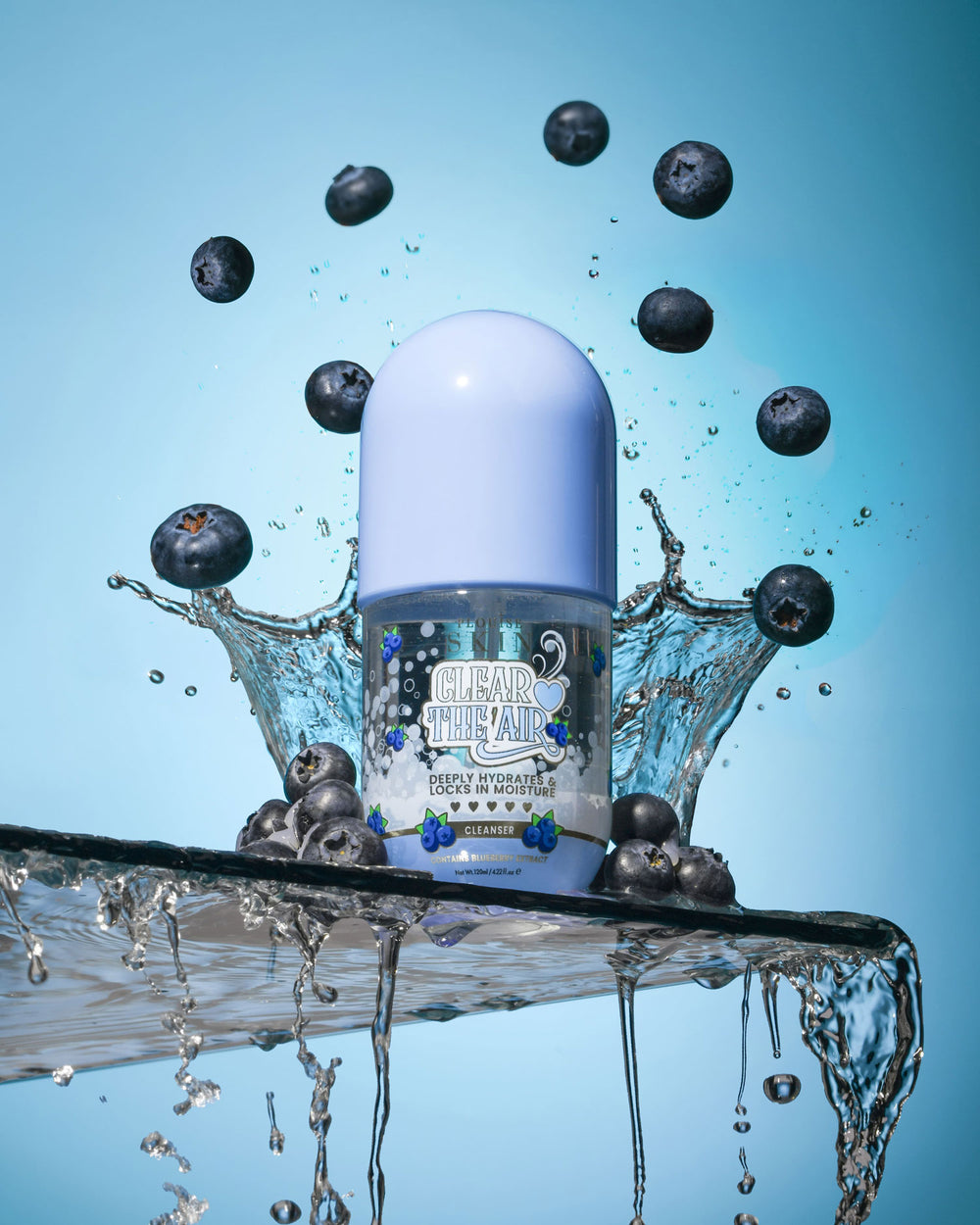 Bouteille de P. Louise Clear The Air Blueberry Gel Cleanserl entouré de myrtilles et d'éclaboussures d'eau sur fond bleu
