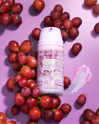 Purple bottle of P. Louise Here I Glow Again Grape Recovery Mask surrounded by grapes on a purple background