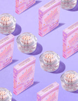 Contenants transparents de crème pour le visage P.Louise DOse of Dreams Viatmin C Capsule contenant une capsule rose entourée de boîtes de céréales roses sur fond violet