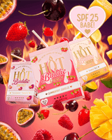 Three juice boxes from Hot Baddie Energy SPF Lip Conditioner and Lip Oil Duo are arranged in a dynamic floating composition surrounded by fresh fruit slices, cherries, strawberries, and passion fruit on a vibrant pink and orange background with flame graphics. 