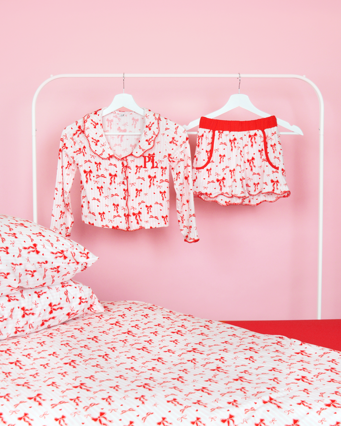 Ensemble de pyjamas filles à rayures roses et blanches P.Louise short de pyjama à nœud de Noël sur cintres dans une chambre rose avec literie assortie 