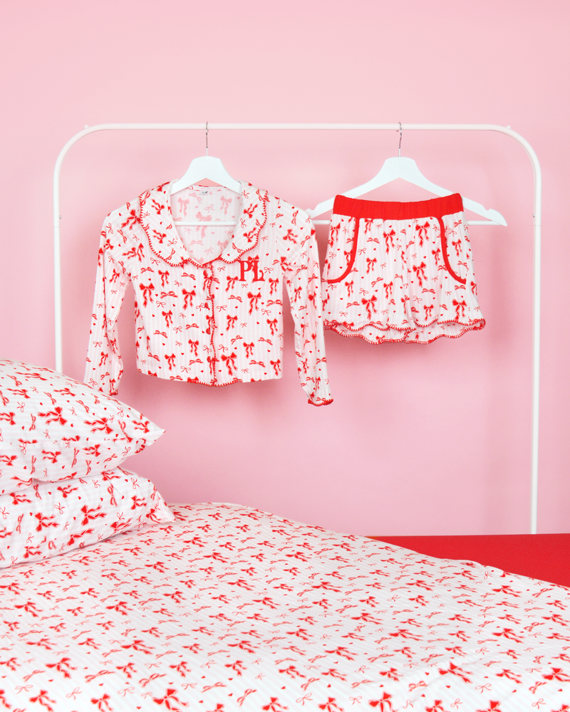 Ensemble de pyjamas filles à rayures roses et blanches P.Louise short de pyjama à nœud de Noël sur cintres dans une chambre rose avec literie assortie 