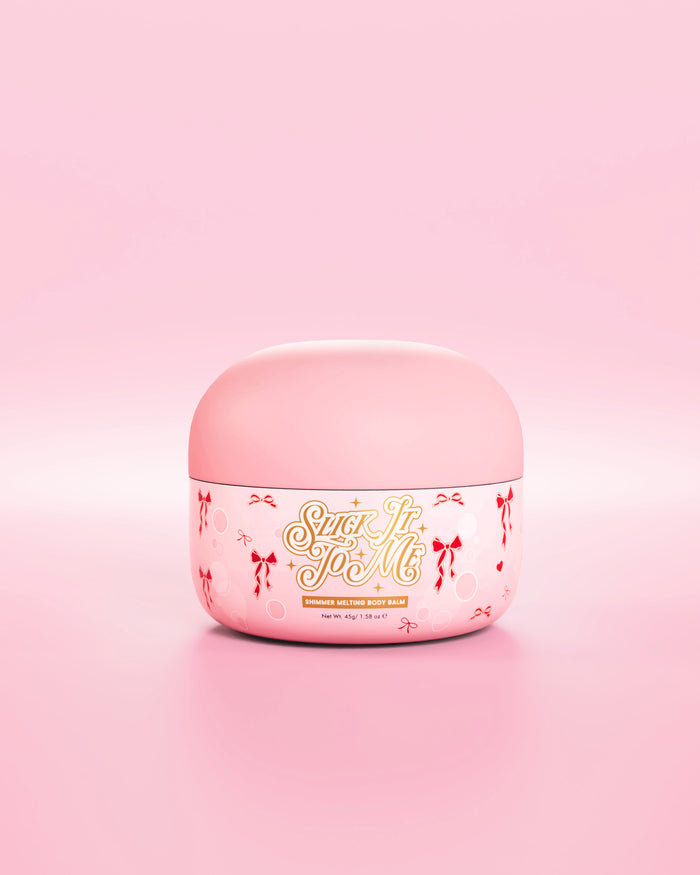 Pot rose de baume pour le corps fondant et chatoyant SLick It To Me avec éléments décoratifs en forme d'arc rouge sur fond rose