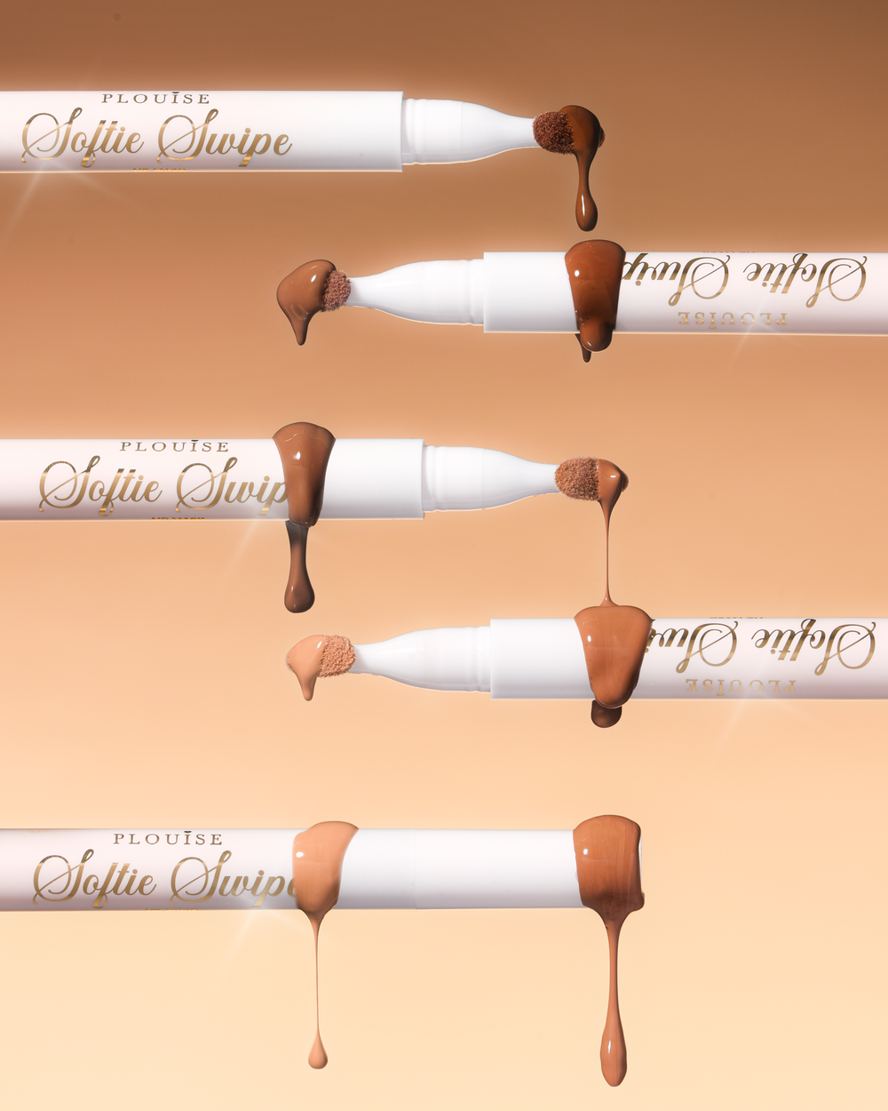 Une image de cinq masques à lèvres teintés P.Louise Softie Swipe avec du produit dégoulinant des pointes montrant les différentes nuances sur un fond beige