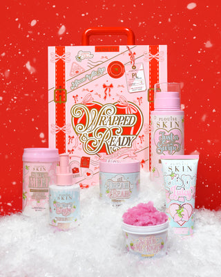 Collection of P.Louise skincare products with a decorative festive suitcase with Wrapped & Ready written on it in gold foil on a red background surrounded by snow