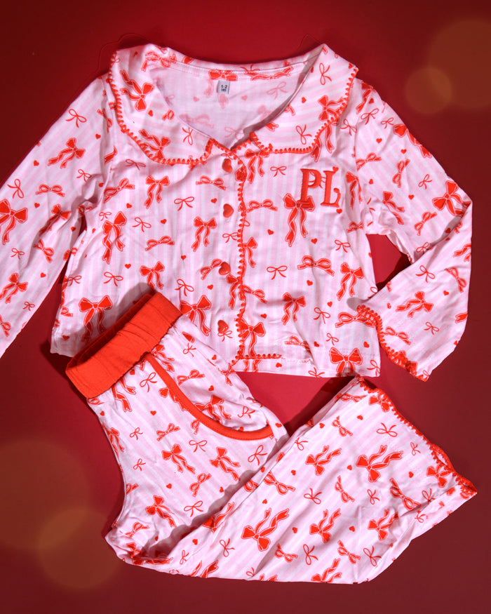 Ensemble de pyjamas de Noël pour enfants à rayures roses et blanches avec des motifs d'arcs rouges sur un fond rouge