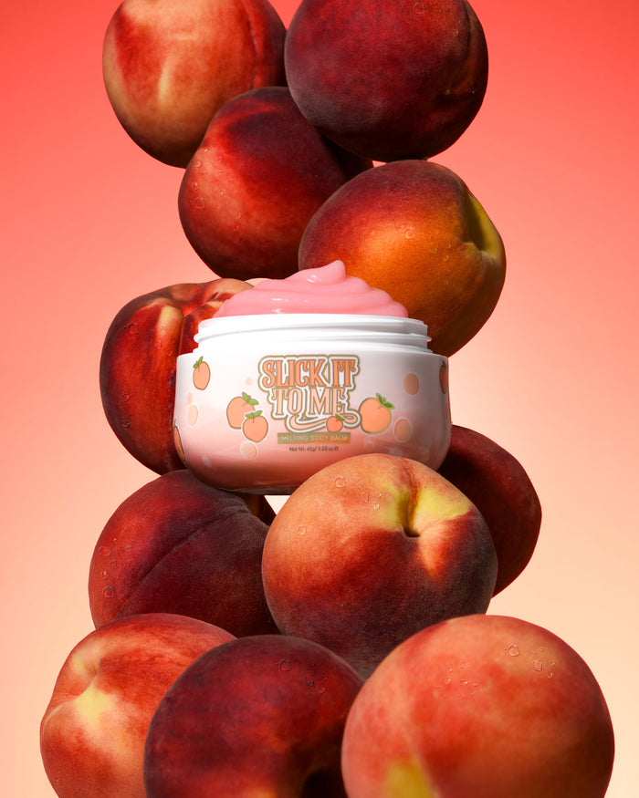 Pot de P. Louise Slick It To Me Baume Corps Fondant Pêche à la crème rose entouré de pêches sur fond dégradé