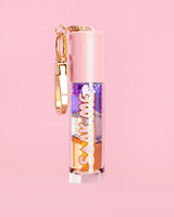 P. Louise Soak Me Lip Oil avec de l'huile en couches colorées dans un tube rose avec un fermoir doré sur fond rose
