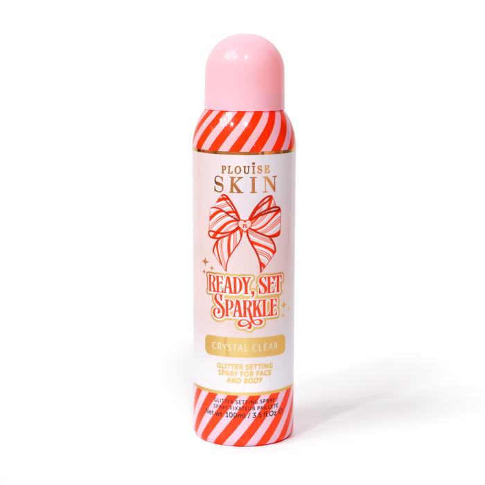Une bouteille de P. Louise Ready Set Sparkle Christmas Glitter Setting Spray avec des rayures rouges et roses sur la bouteille et un nœud rayé rouge et rose sur fond blanc