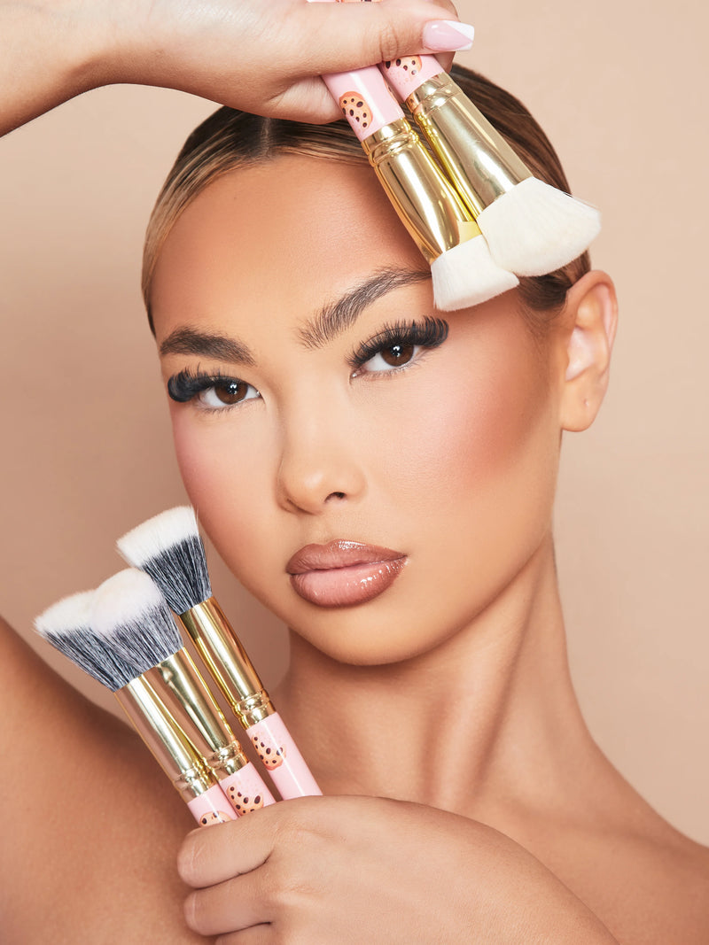Image d'une femme mannequin maquillée tenant l'ensemble de 5 pinceaux de maquillage pour le visage Spoiled For Choice de P.Louise contre son visage.