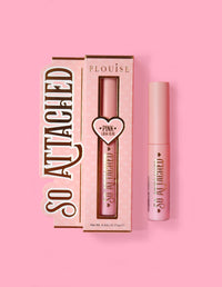 L'emballage du produit P.Louise So Attached Lash Glue et le tube de colle lui-même, placés sur un fond rose.