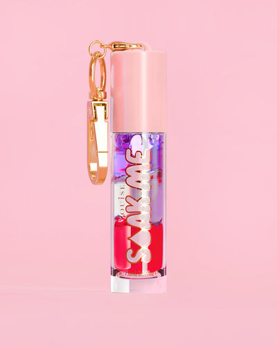 P. Louise Soak Me Lip Oil avec de l'huile en couches colorées dans un tube rose avec un fermoir doré sur fond rose