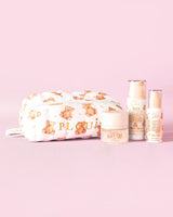 Une image du kit de démarrage de soins de la peau P.Louise Softest Touch avec une trousse de soins de la peau et de maquillage en forme d'ours en peluche en gros caractères et 3 produits de soins de la peau sur fond rose